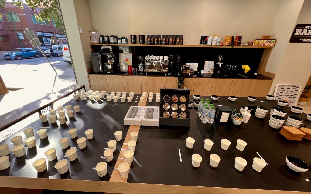 Academia Barista by Nestlé: espacio de formación en café con mesa de cata, aromas y evaluación sensorial. Estantería con variedades de café y té, junto a equipos de barismo